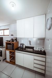 a kitchen with white cabinets and a sink at Apartamento com garagem a 200m da Praia do Bessa in Tambaú