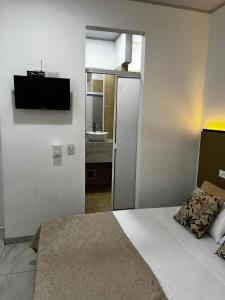a bedroom with a bed and a tv on the wall at La Puerta del Ángel LOW COST in Ricaurte