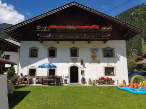 a white house with a balcony with flowers on it at Griesshof in Neustift im Stubaital