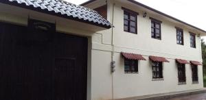 een wit huis met een zwarte garagedeur en ramen bij Hotel Campestre El Rinconcito de Chigna in Chignahuapan