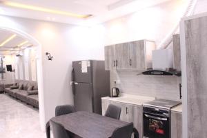 Una cocina con refrigerador y una mesa y sillas. en شاليهات ديم لايت, en Az Zulfi
