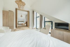 ein weißes Schlafzimmer mit einem großen Bett und einem Spiegel in der Unterkunft Premium By Míra Hejda in Vítkovice