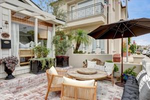 eine Terrasse mit Tisch und Stühlen und einem Sonnenschirm in der Unterkunft Balboa Island Beach Cottage in Newport Beach