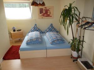 Un dormitorio con una cama azul con almohadas y una planta en Fewo Reyersviller en Reyersviller