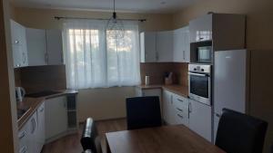 a kitchen with white cabinets and a table and a window at Konstantin Apartman in Szolnok