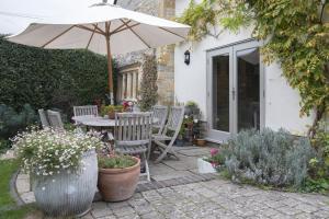 a patio with a table with an umbrella and chairs at Idyllic Cotswold Cottage Near Broadway in Badsey