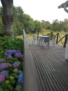 a wooden deck with a table and chairs and flowers at Cabaña en el campo in Puyehue