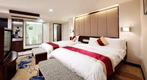 una camera d'albergo con due letti e una televisione di New World Hotel a Canton