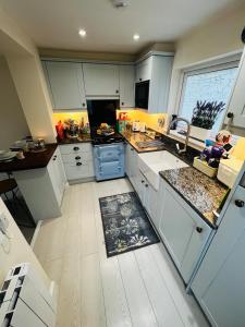 a large kitchen with white cabinets and a sink at Angel Cottage, Strone in Dunoon