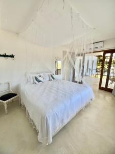 ein Schlafzimmer mit einem großen weißen Bett mit Schnüren in der Unterkunft Casa do Sol in São Miguel do Gostoso