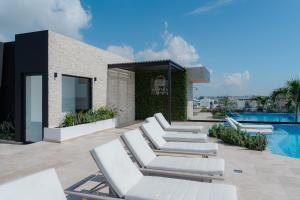 a group of lounge chairs sitting next to a swimming pool at New Luxury Studio in the City Center in Playa del Carmen