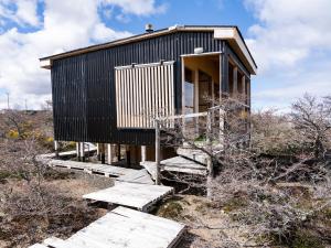 Cabañas Sierra Dorotea في بويرتو ناتالز: منزل على تلة به درج ومقاعد