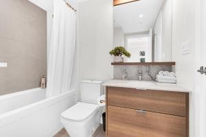 a bathroom with a toilet and a sink and a tub at Parkside at Waterfront in Downtown Calgary in Calgary