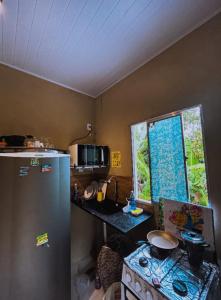 a kitchen with a refrigerator and a table and a window at Apartamento Reserva Sapiranga in Praia do Forte