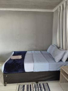a bedroom with a bed with blue sheets and pillows at Just Bed&Bath by Mama R in Newcastle