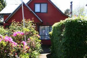 a red house with some flowers in front of it at Pucón Forest Wellness in Pucón