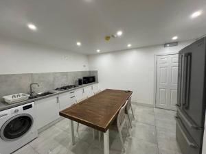 une cuisine avec une table en bois et un lave-linge dans l'établissement Modern en-suite rooms Luton air port, à Luton