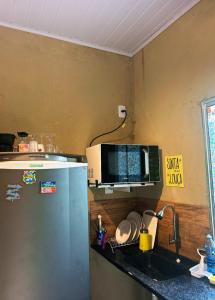 a kitchen with a refrigerator and a microwave on a counter at Apartamento Reserva Sapiranga in Praia do Forte