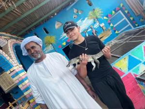 two men holding a lizard in front of a wall at Katadool Boat in Aswan
