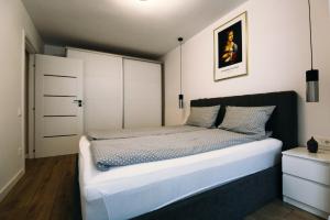 een slaapkamer met een groot bed en witte kasten bij DaVinci Apartment with Self Check-In in Târgu-Mureş
