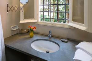 La salle de bains est pourvue d'un lavabo avec un vase de fleurs et d'une fenêtre. dans l'établissement Giardino in villa Margherita, à Zoagli