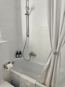 een wit bad met een douchegordijn in de badkamer bij Modern City Apartment 1 in München +16 foto's