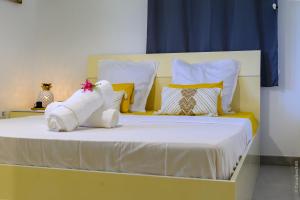 Cama con sábanas y almohadas amarillas y blancas en Kayna, en Sainte-Luce