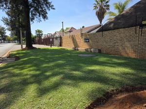 un patio de hierba junto a un edificio de ladrillo en Swiss Guest House, en Vanderbijlpark