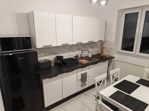 a kitchen with white cabinets and a black refrigerator at Terra Ștrand Residence Ștei in Doctor Petru Groza