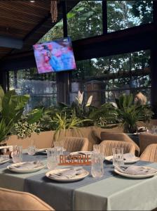a table with plates and glasses and a tv in a restaurant at Radamis Hotel in Almaty