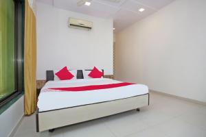 a bedroom with a bed with red pillows at Hotel O Capital O Sai Icon Residency in Titwala