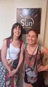 two women standing next to each other in front of a sign at Sun City in Aswan