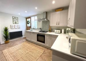 a kitchen with white cabinets and a stove top oven at PRIMROSE COTTAGE, Sleeps 5, Stylish Cottage, Central, Close to Beach, shops and restaurants in Beer