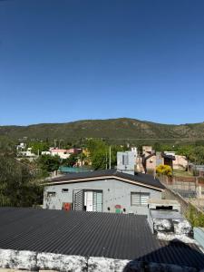 a white building with a mountain in the background at Cabañas Pindahue - Alojamiento Huilen in Villa Carlos Paz