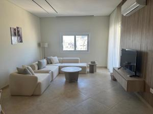 a living room with a white couch and a tv at Mozaik Condotel in Cairo