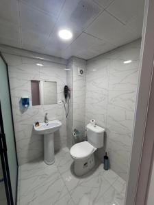 a white bathroom with a toilet and a sink at Old City Kadıköy Otel in Istanbul