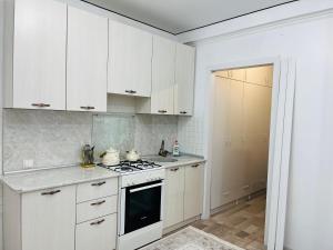 a kitchen with white cabinets and a stove top oven at Каратал 6Б in Taldykorgan
