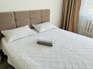 a white bed with two pillows and a towel on it at Каратал 6Б in Taldykorgan