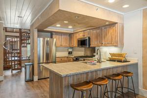 a kitchen with wooden cabinets and a island with bar stools at Tamarron Lodge #752 in Rockwood +15 photos
