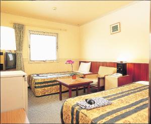 a hotel room with two beds and a table at Hotel Taira in Naha