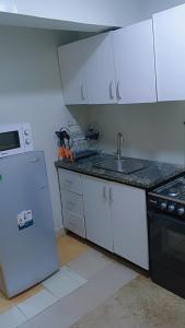 a kitchen with white cabinets and a sink and a refrigerator at Royale Signature in Lagos