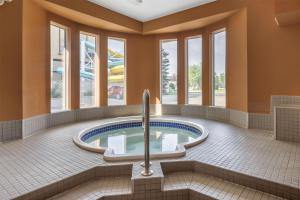 a jacuzzi tub in a building with windows at SureStay Plus Hotel by Best Western Lethbridge in Lethbridge