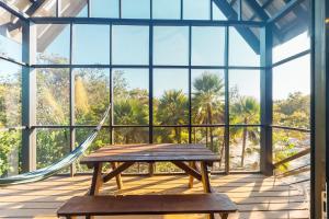 a hammock on a porch with a table and a swing at Black Orchid Cabaña at Inn The Trees -Gold Standard Certified in Seine Bight Village