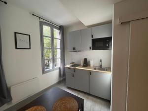 una cucina con mobili bianchi, un lavandino e una finestra di Pia - Studio 1er climatisé 2 pers ad Avignone