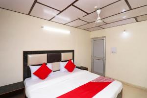 a bedroom with a large bed with red pillows at Hotel O Country Lodge in Dharamshala