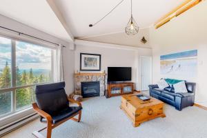 a living room with a couch a chair and a television at Hilltop Hideaway - Legacy 401AB in Big White