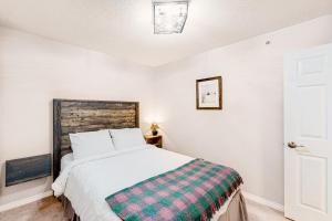 a bedroom with a bed with a checkered blanket on it at Hilltop Hideaway - Legacy 401AB in Big White +21 photos