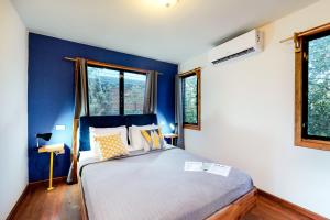 a bedroom with a bed with blue walls and windows at Toucan Cabaña at Inn The Trees -Gold Standard Certified in Seine Bight Village