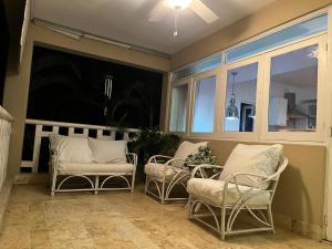 porche con sillas, mesa y ventanas en Antiguo Dominican Bay, en Cuevas