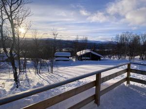 een besneeuwde tuin met een hek en een huis bij Stugan i Åsvallen in Tänndalen